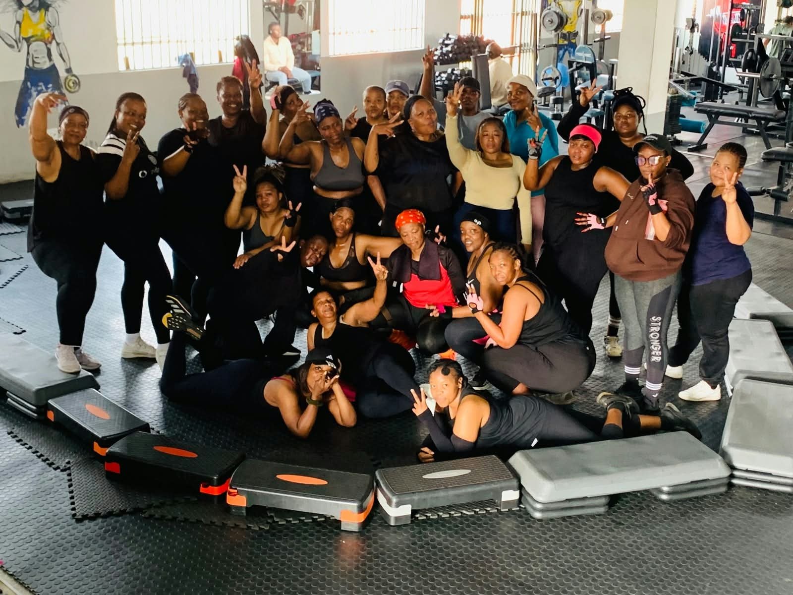 Women runners dressed in black pose at Workout Zone Base Gym before a 10km memorial run in Dawn Park.